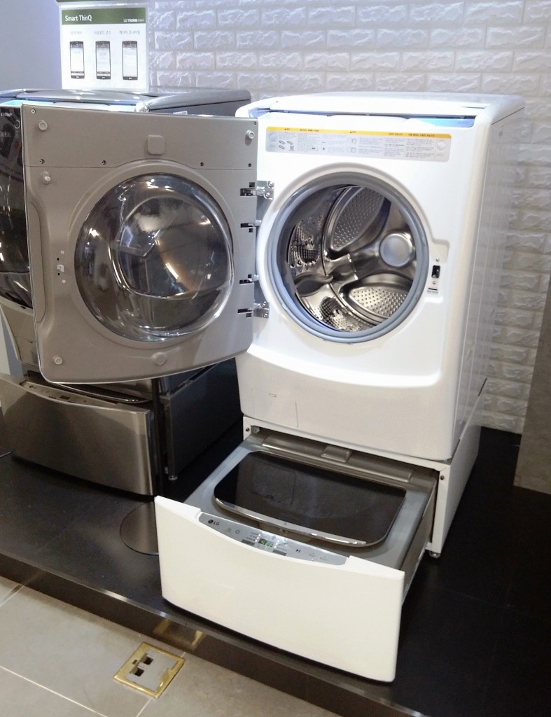 LG TWINWash™ washing machine in white color with front-load on the top and mini top-load at the bottom. Both washers are opened.