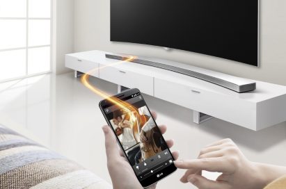 Front view of the LG Curved Sound Bar with a model controlling it via the Soundbar Smartphone App Controller