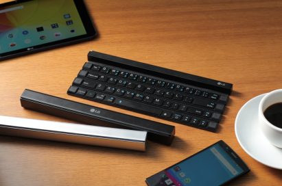 Three Rolly Keyboards displayed on the table with a G pad, an LG smartphone and a cup of coffee. Two of them are folded up with the other is ready to use.