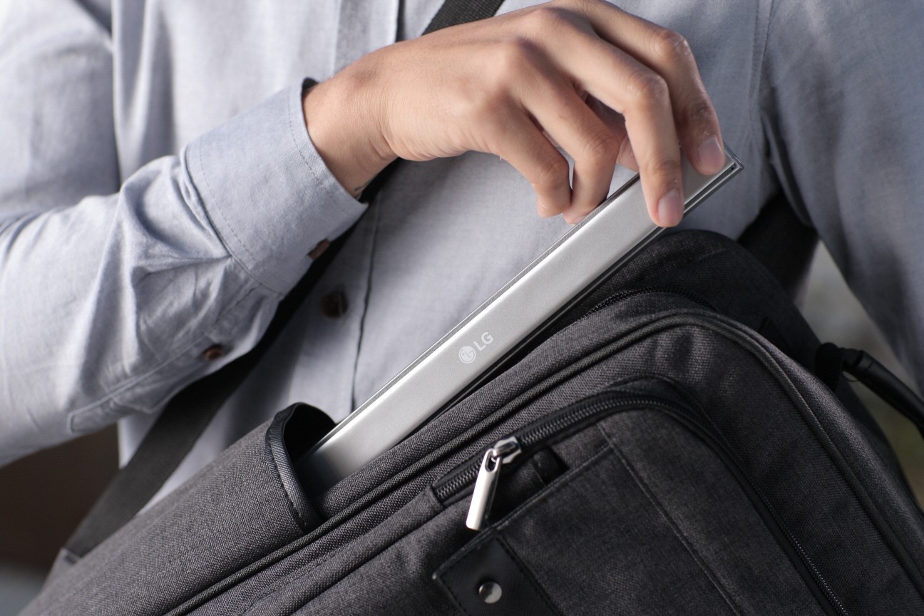 A man taking his folded Rolly Keyboard out of the side pocket of his backpack.