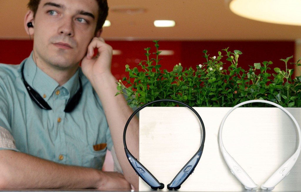 A man is listening to music with LG TONE ULTRA HBS-810 resting his chin on his hand. And a white TONE ULTRA HBS-810 and a black one are displayed in front of him.