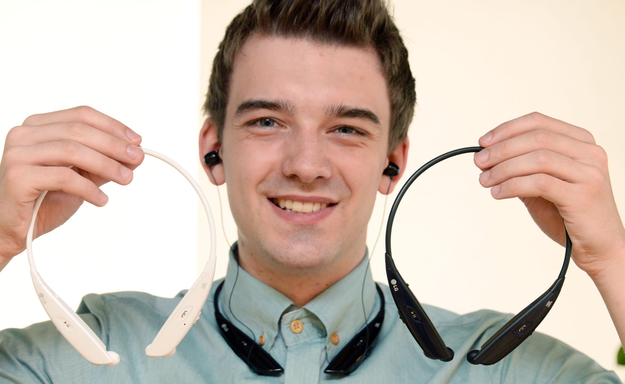 A man wearing a TONE ULTRA HBS-810 holds two more TONE ULTRA HBS-810s in black and white.