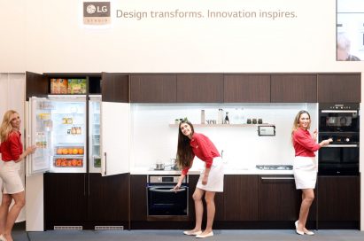 Three female models posing with LG Studio refrigerator, oven and Speed oven.