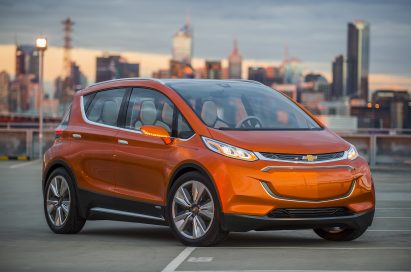 The Chevrolet Bolt EV (electric vehicle) with a city skyline backdrop.