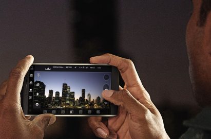 A man takes a photo of a city skyline at night with the LG V10