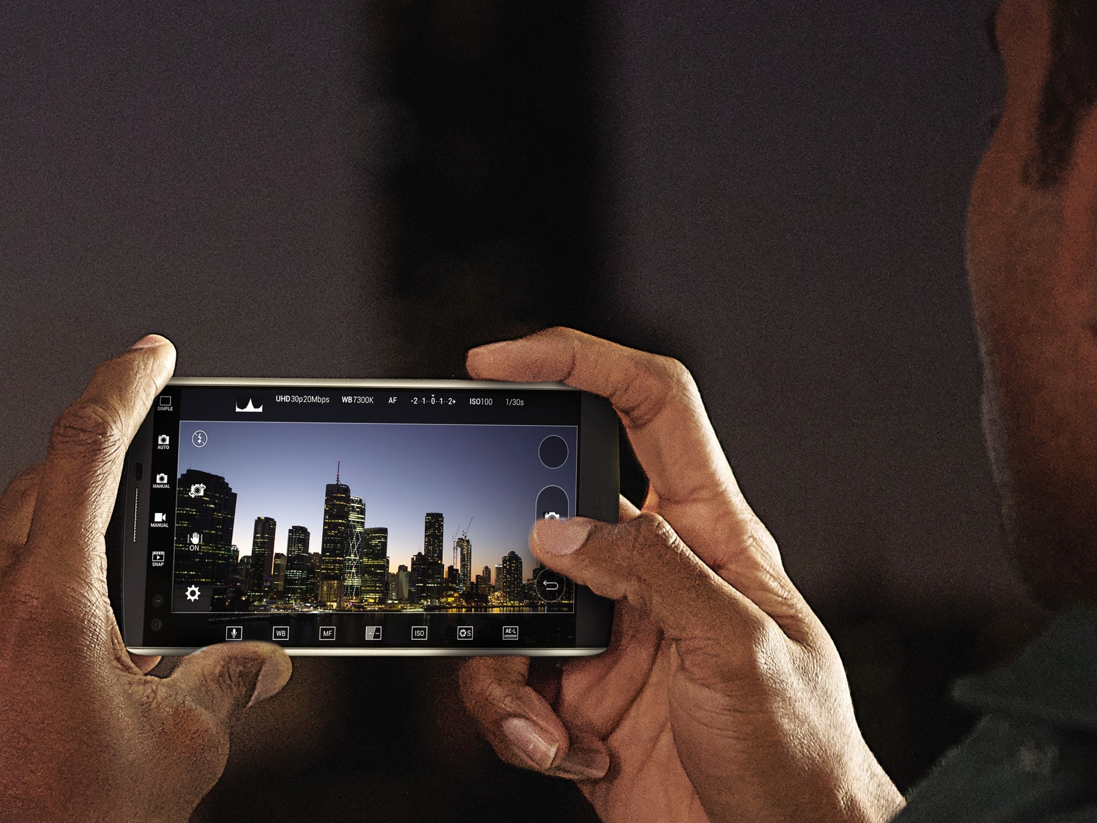 A man takes a photo of a city skyline at night with the LG V10