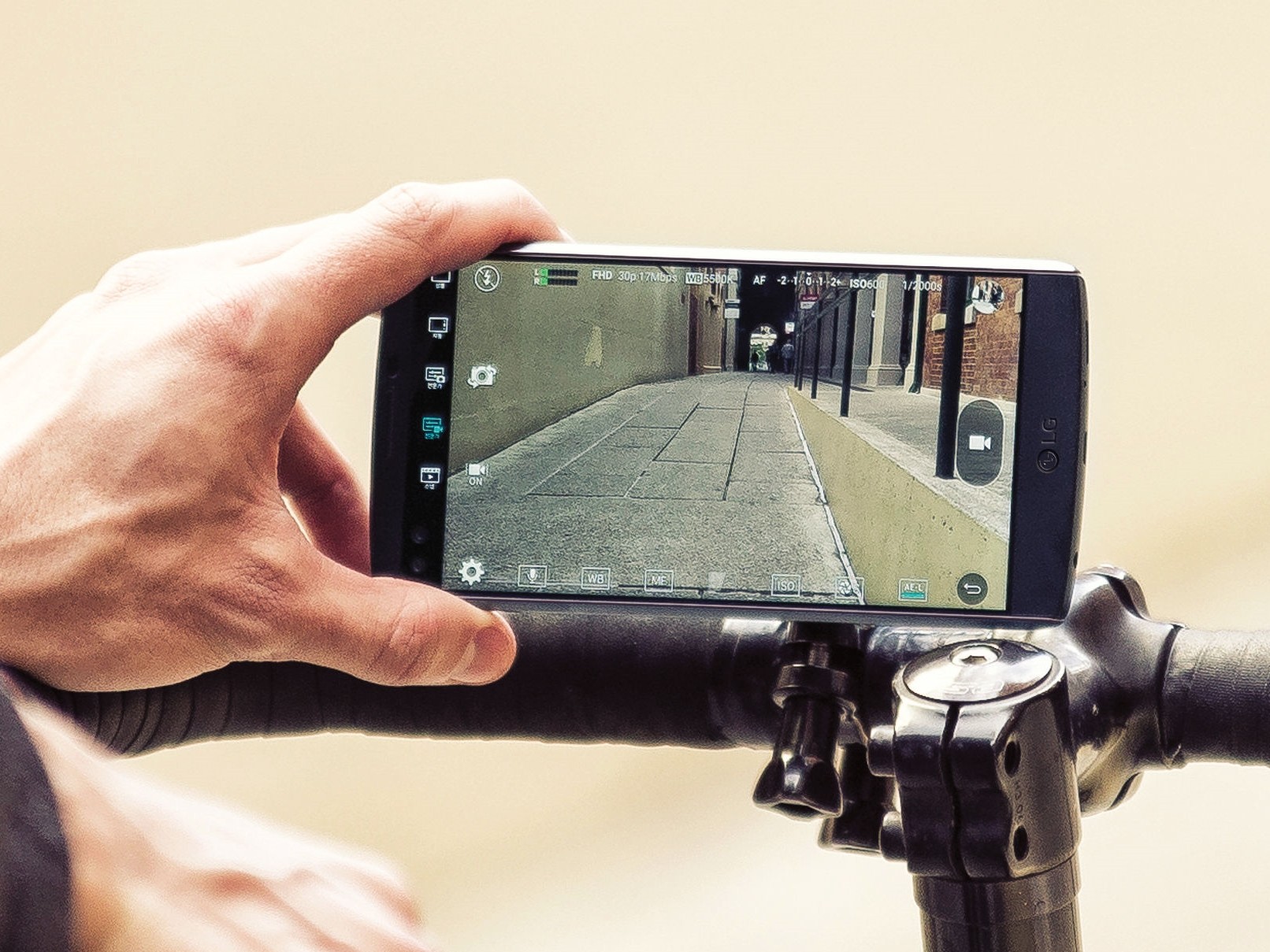 A person records a video on LG V10 propped on top of bicycle handles