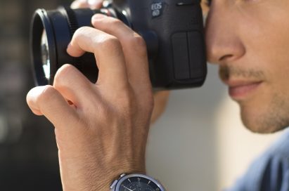 A man with the LG Watch Urbane 2nd Edition on his wrist takes a photo with a DSLR camera
