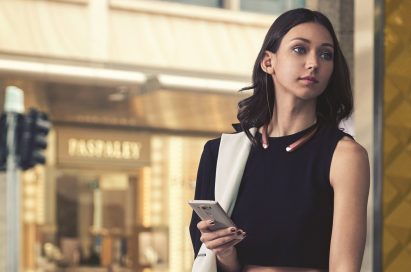 A woman with the LG TONE Infinim™ in Rose Gold around her neck and the retractable ear buds in her ears