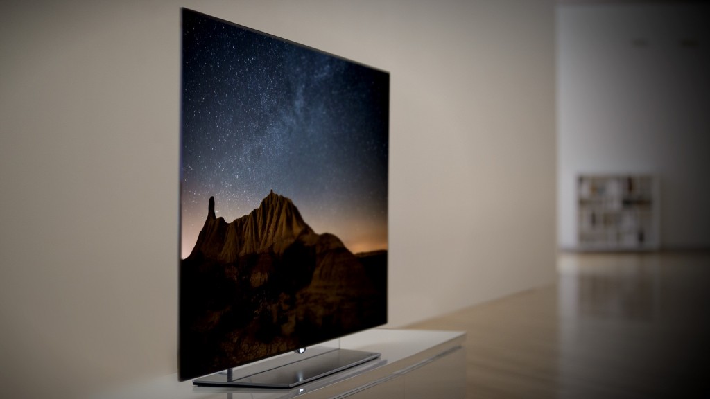 A left-side view of an LG OLED TV displaying a mountain scene at night.