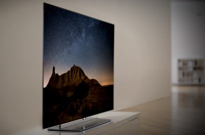 A left-side view of an LG OLED TV displaying a mountain scene at night