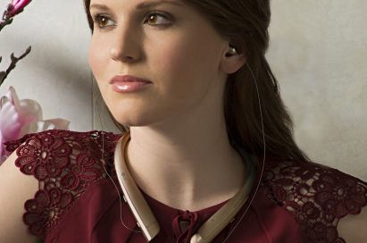 A woman with the LG TONE Platinum™ in Gold around her neck and the retractable ear buds in her ears