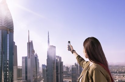 A woman is taking a picture of the skyscrapers in Dubai, United Arab Emirates, with the LG 360 CAM