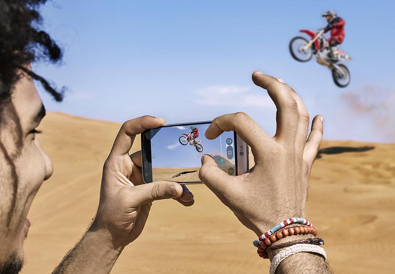 A man is taking a picture of a mountain biker with the LG G5 in White