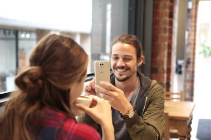 A woman is being photographed by a man with the LG X cam in White