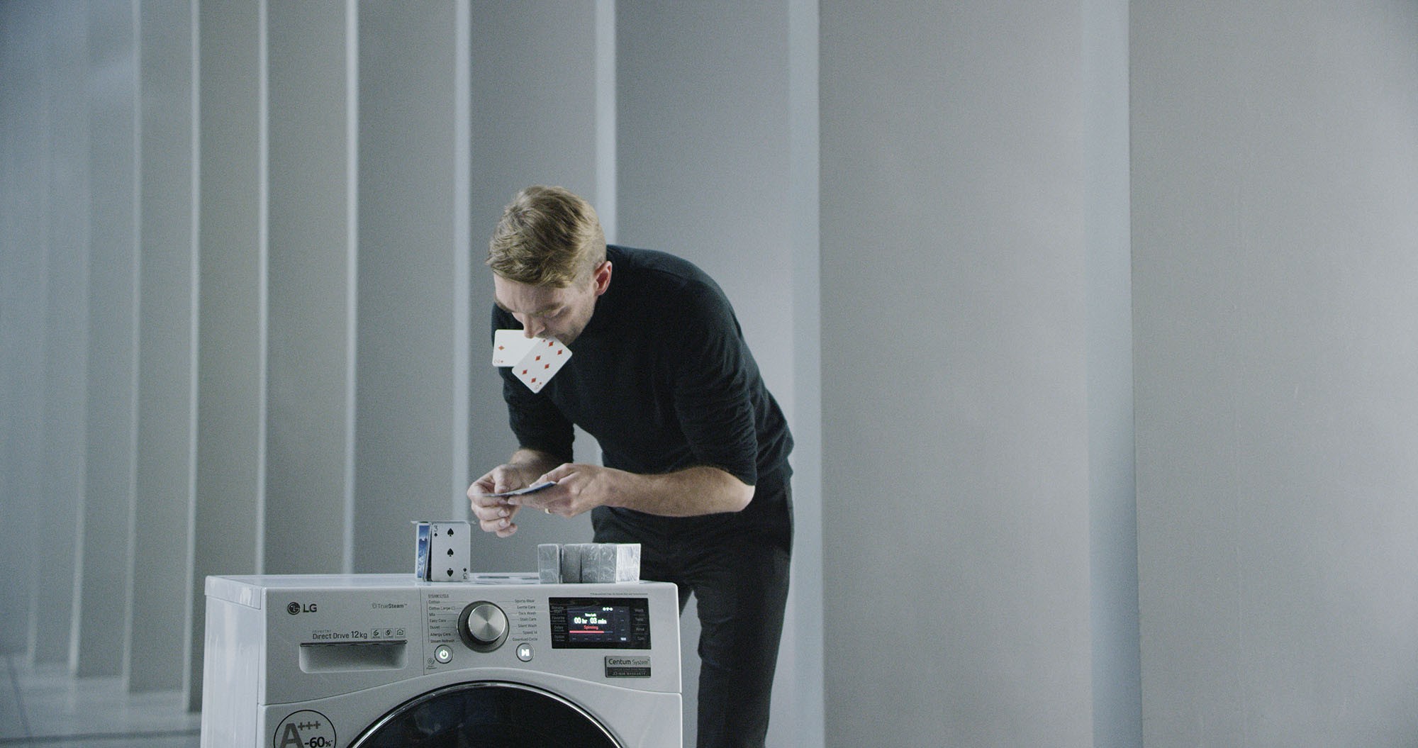 A professional card stacker Bryan Berg building house of card atop an LG Centum System™ washing machine