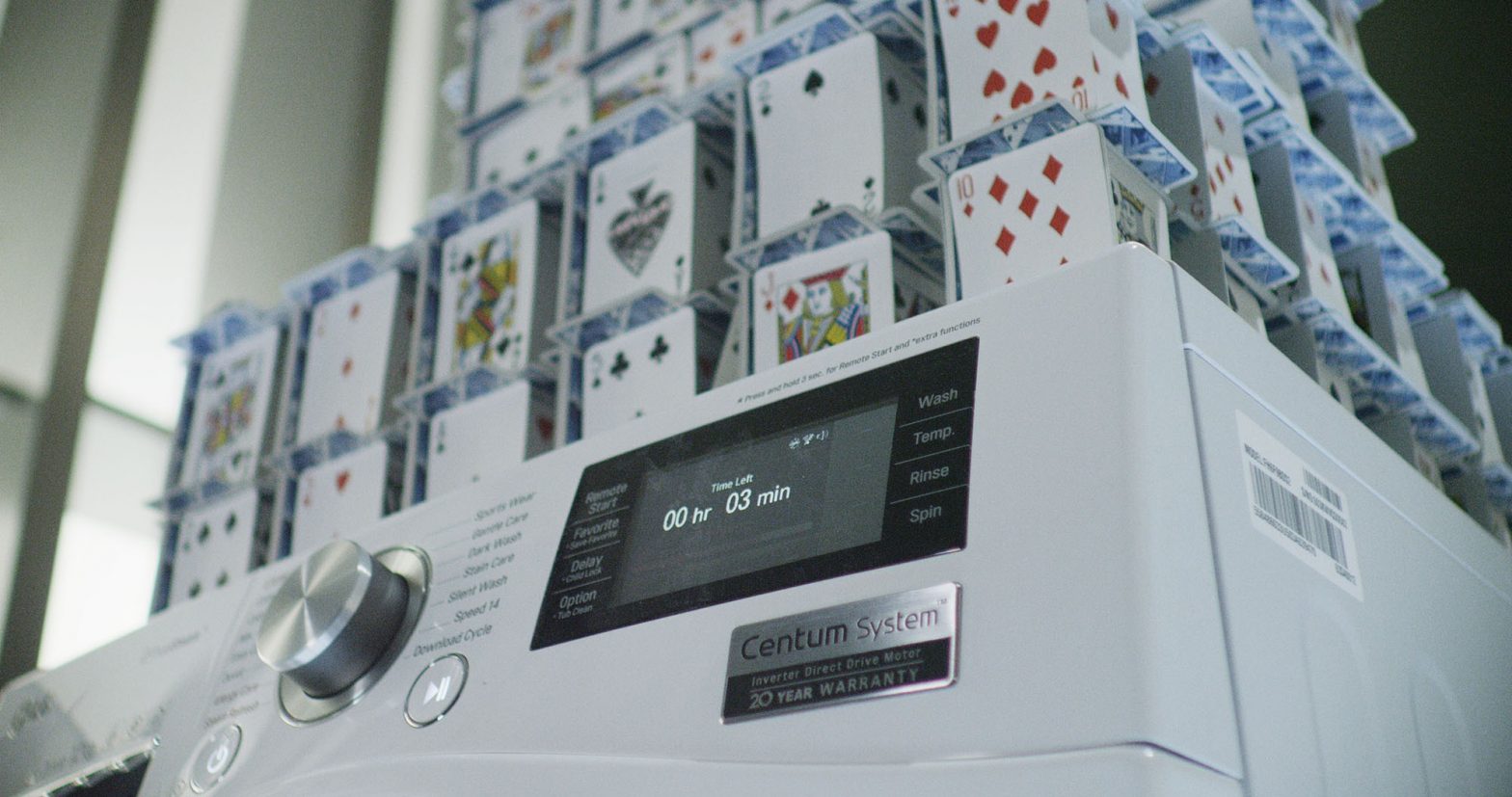 Closeup of LG Centum System™ washing machine and house of card built on it