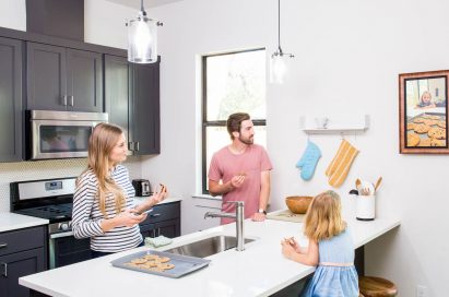 A family of three observe personal photos on their new digital frame by Acanvas in their kitchen.