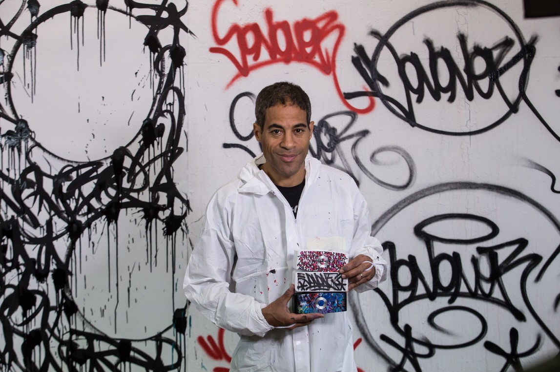 Popular artist JonOne holding up exclusive devices from the LG Portable Speaker art series