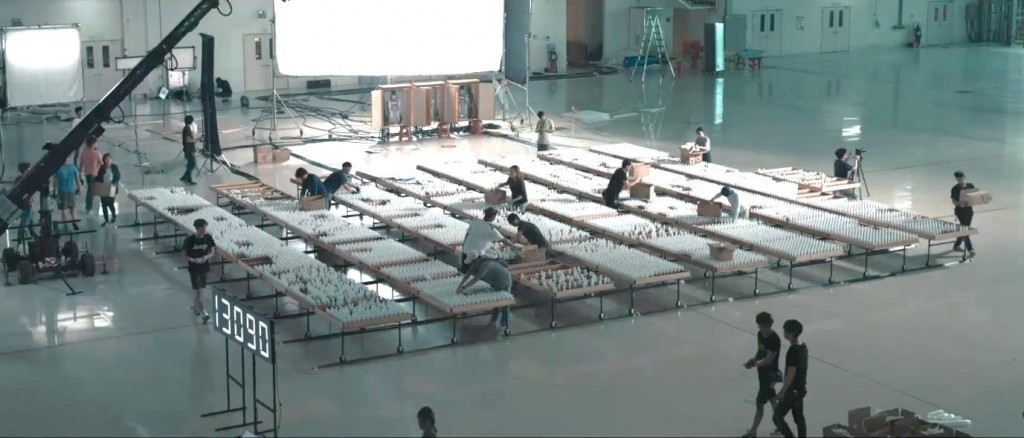 Several people working on constructing the bulb-based display in a large auditorium