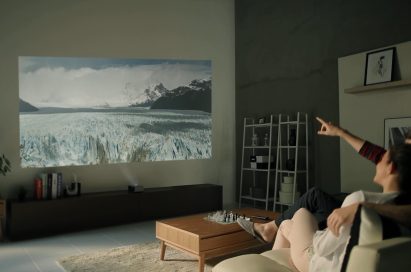 A couple sitting on a couch watching a scene of the Antarctic with the LG Minibeam projector