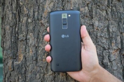 LG K7 smartphone with user’s hand visible, held in front of tree