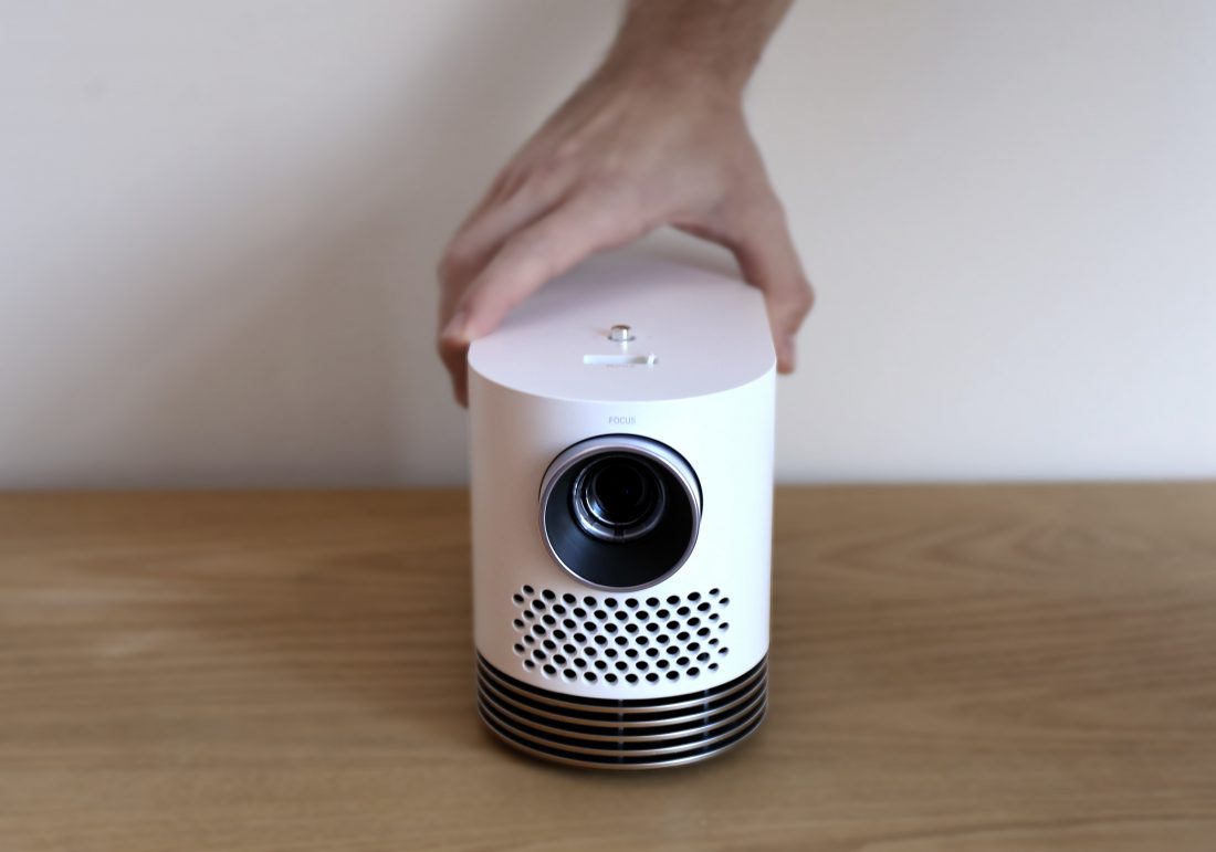Front view of LG Probeam Laser Projector (model HF80J) being put on the desk by a man's hand