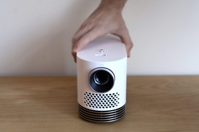 Front view of LG Probeam Laser Projector (model HF80J) being put on the desk by a man's hand