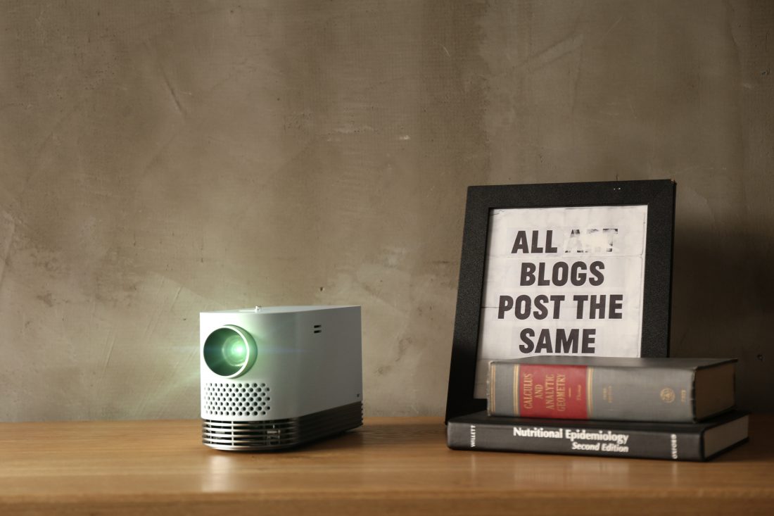 Front view of the LG Probeam Laser Projector (model HF80J) on a table next to books