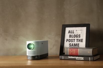 Front view of the LG Probeam Laser Projector (model HF80J) on a table next to books