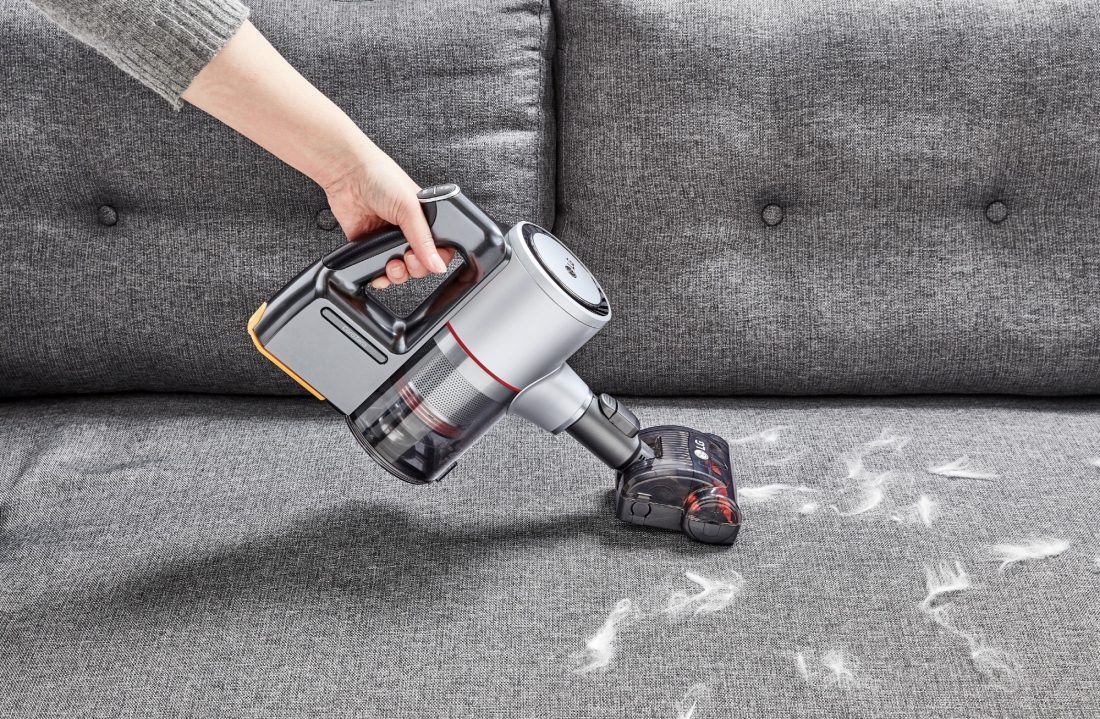 View of a person vacuuming up feathers from a couch with the LG CordZero Handstick