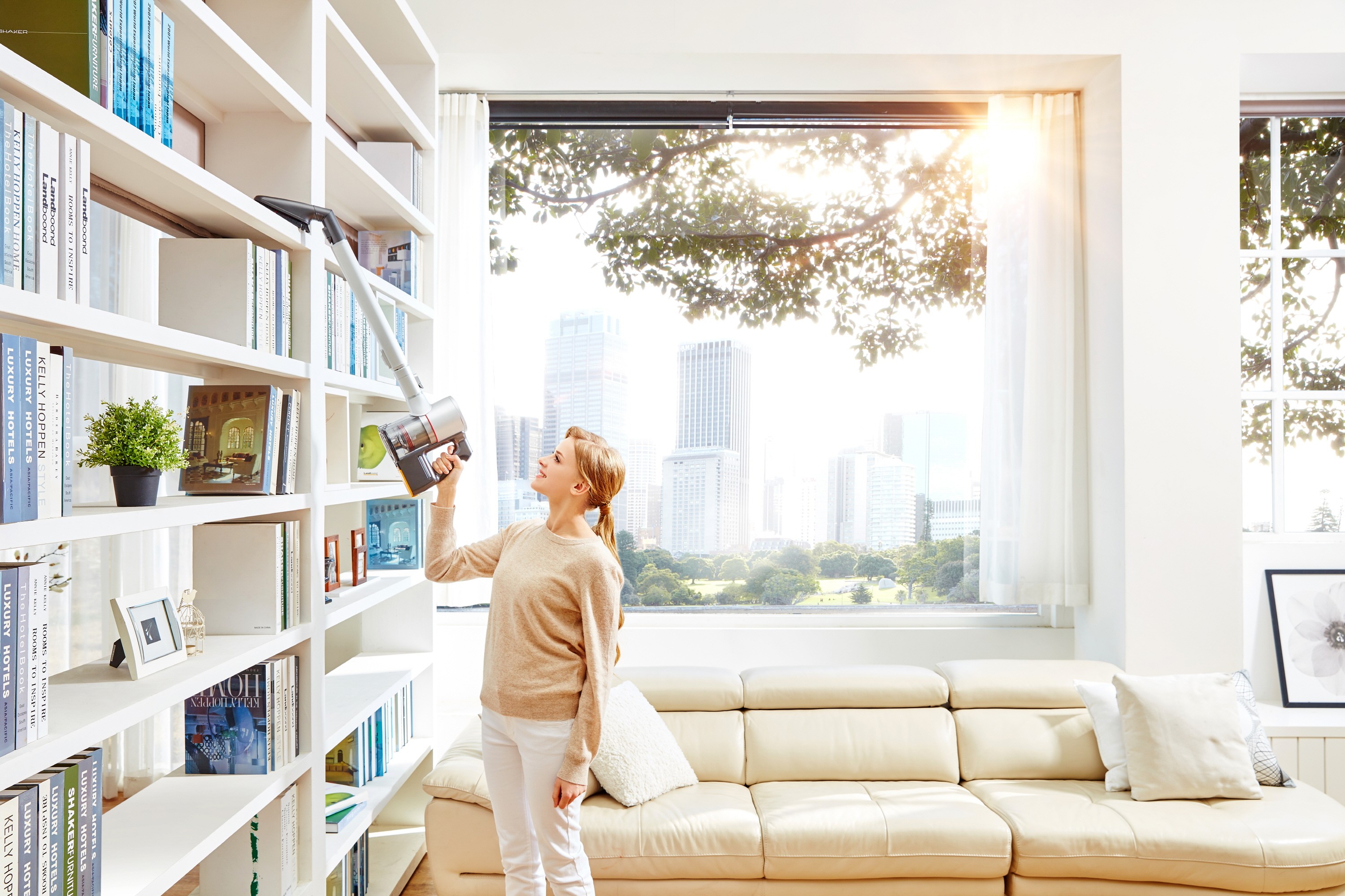 A woman vacuums bookshelves with the LG CordZero Handstick