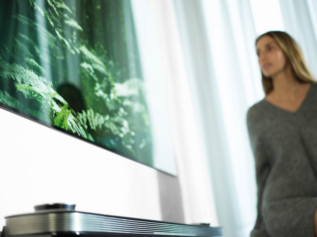 A woman stands looking at the LG SIGNATURE OLED TV W (model W7)