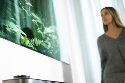 A woman stands looking at the LG SIGNATURE OLED TV W (model W7)