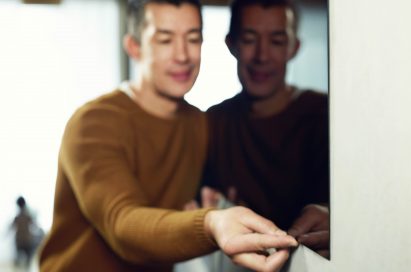 A man tries to tug on the screen of an LG SIGNATURE OLED TV W which hangs flush against the wall.