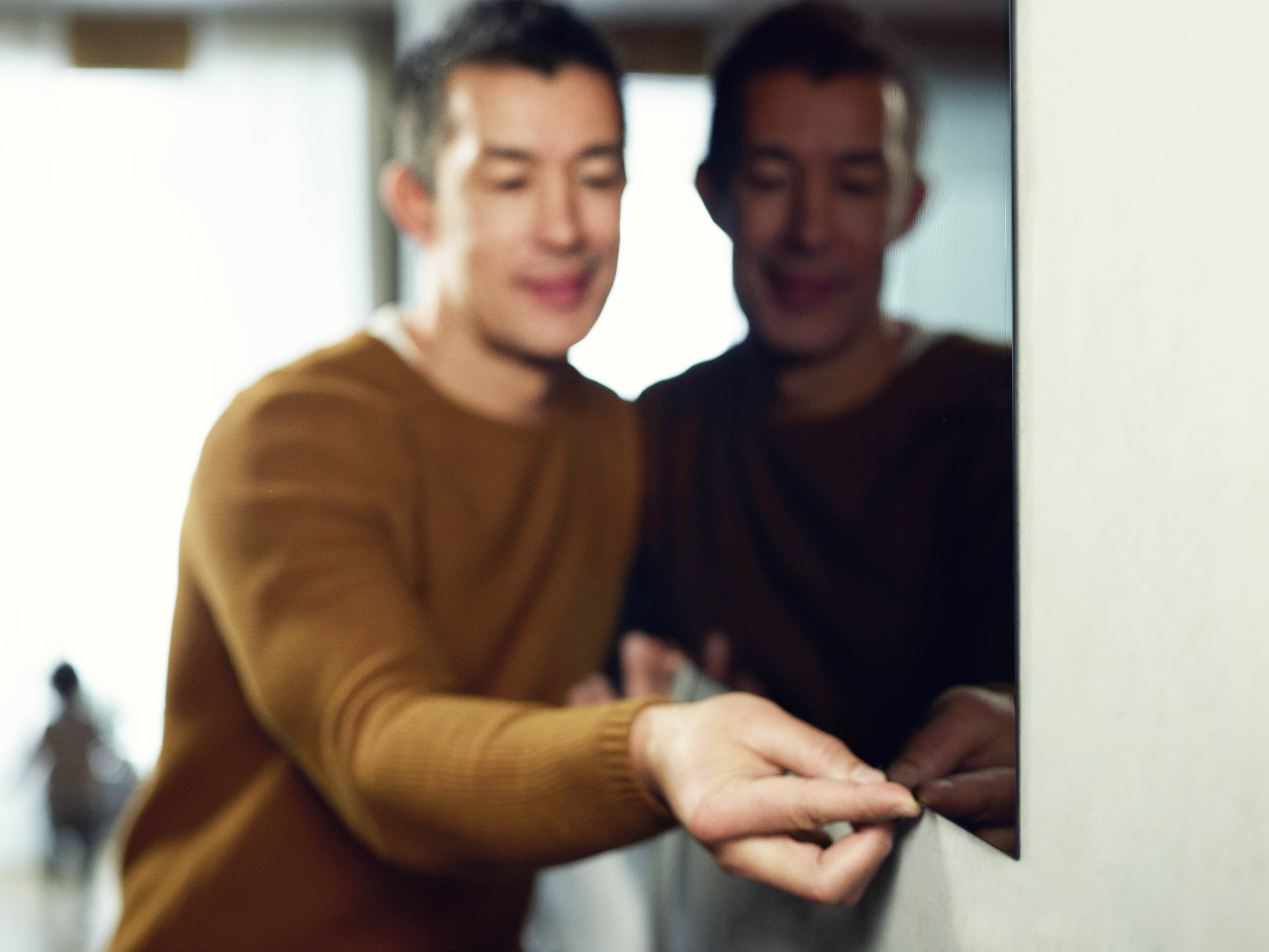 A man tries to tug on the screen of an LG SIGNATURE OLED TV W which hangs flush against the wall.
