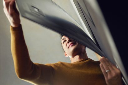 A man tugs on the bottom of the screen of LG SIGNATURE OLED TV W and admires the slender form of it.