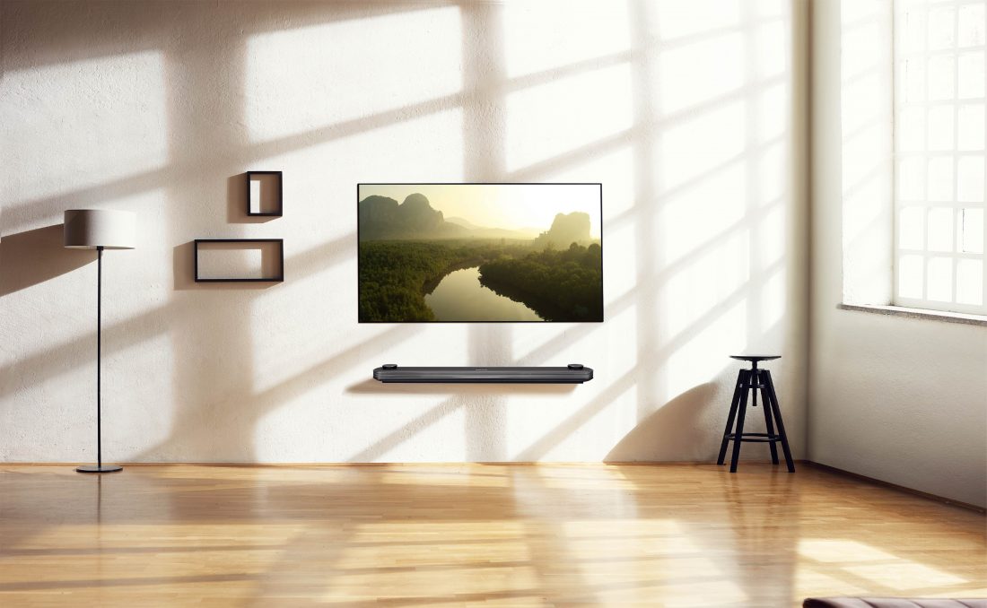 An LG SIGNATURE OLED TV W is on the wall of an apartment with some interior décors while displaying a nature scene on its screen.