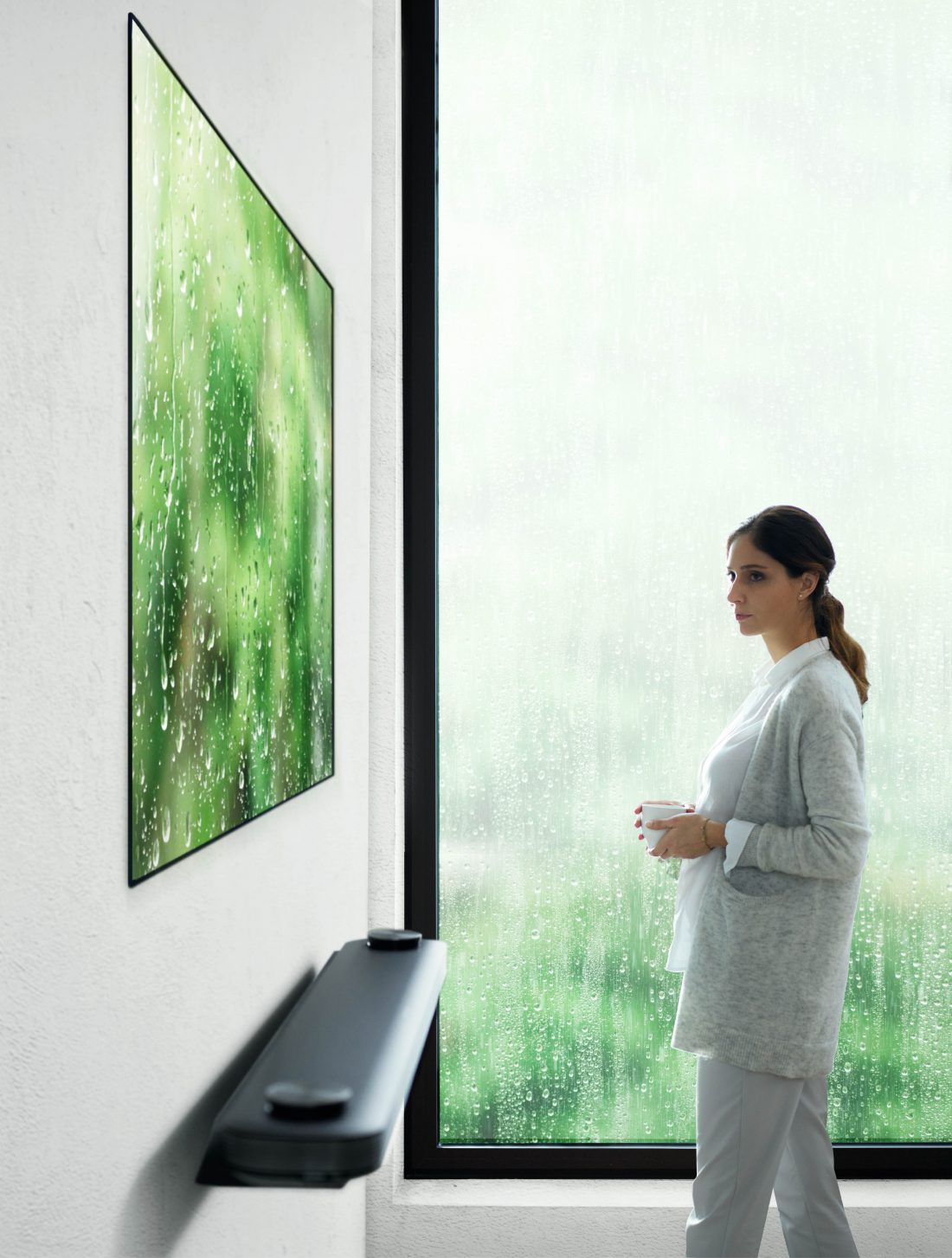 Another view of a woman standing looking at the LG SIGNATURE OLED TV W (model W7)