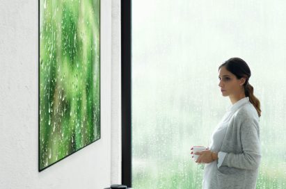 Another view of a woman standing looking at the LG SIGNATURE OLED TV W (model W7)