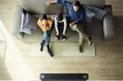 Another view of a family sitting in their living room looking at the LG SIGNATURE OLED TV W (model W7) which is mounted on the wall