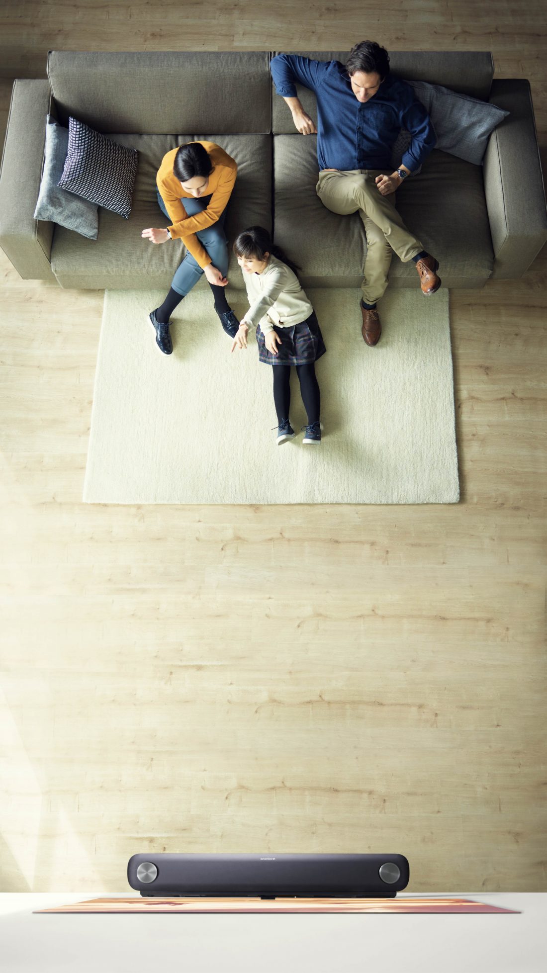 A family sits in their living room looking at the LG SIGNATURE OLED TV W, which hung flush against the wall