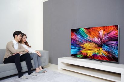 A couple sits on a couch watching the LG SUPER UHD TV (model SJ95).