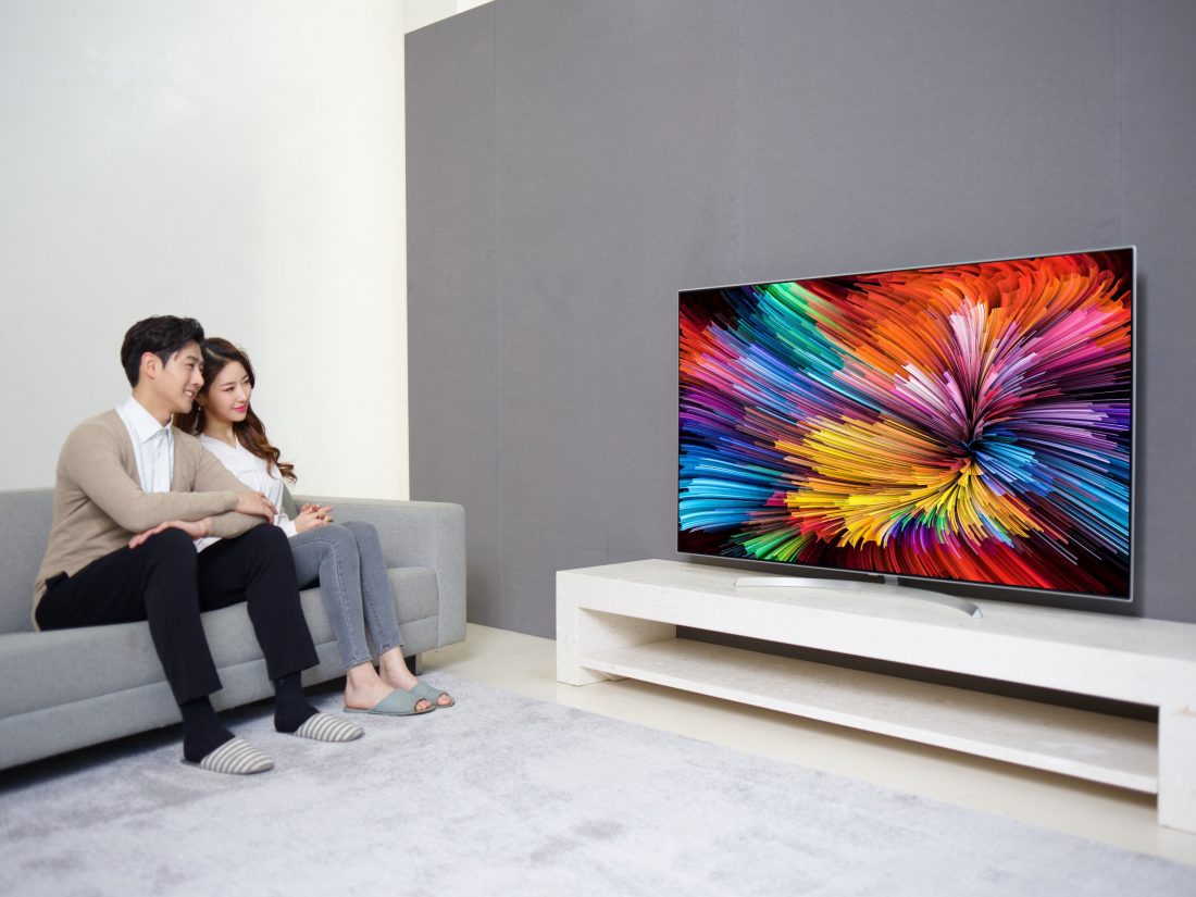 A different shot of a couple sitting on a couch watching the LG SUPER UHD TV (model SJ95)