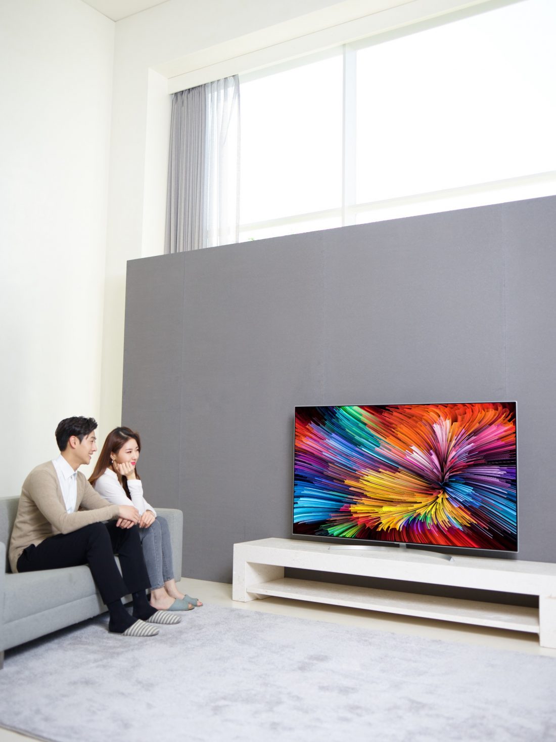 Another view of a couple sitting on a couch watching the LG SUPER UHD TV (model SJ95)