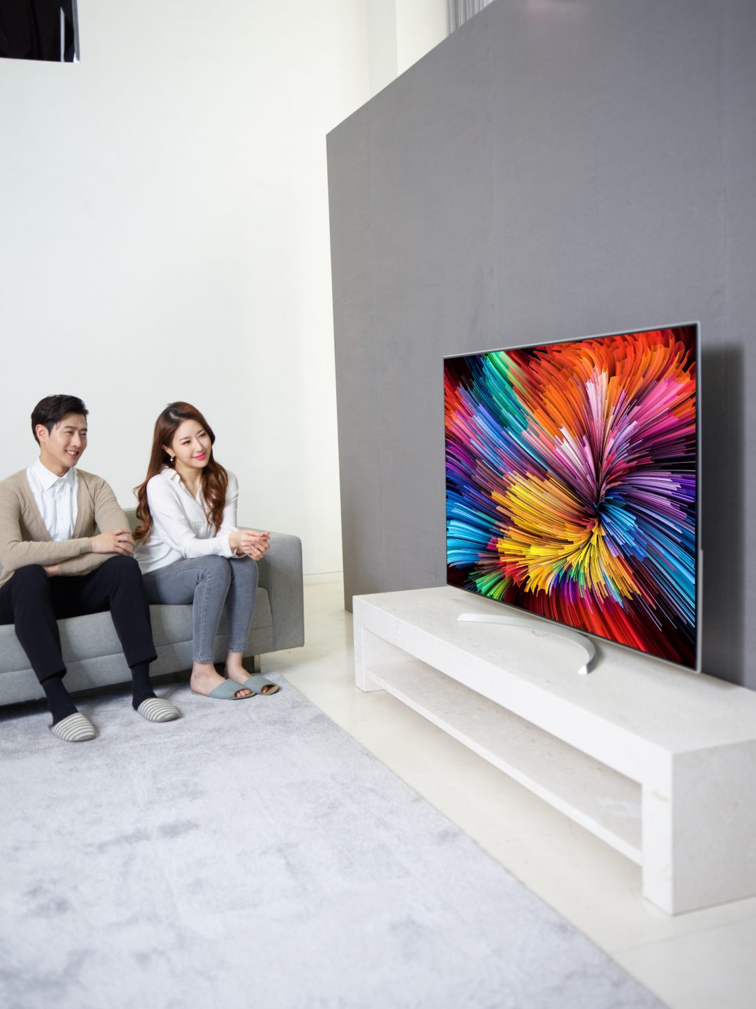 Another different shot of a couple sitting on a couch watching the LG SUPER UHD TV (model SJ95)