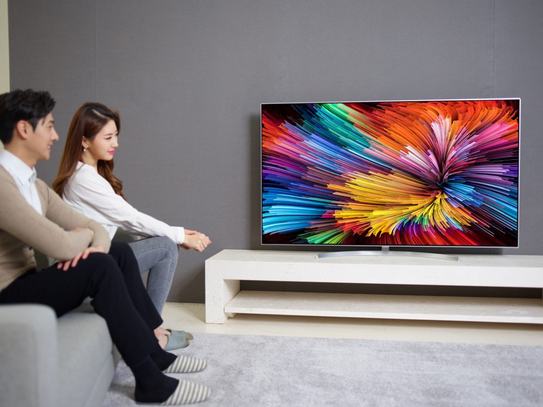 The other view of a couple sitting on a couch watching the LG SUPER UHD TV (model SJ95)