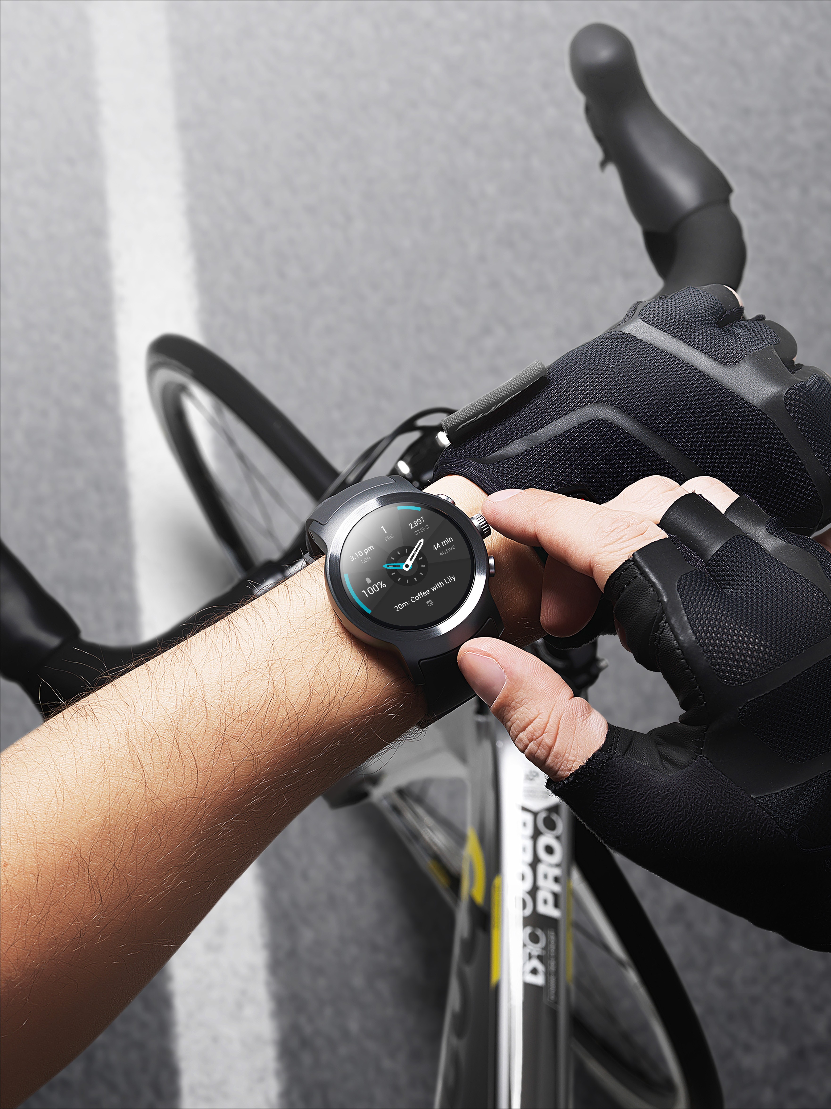 A man touching his LG Watch Sport in Titanium while taking a break from cycling