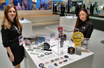 Two LG promoters standing behind two LG G6 devices and 31 booth awards that were given to the LG G6 at MWC 2017