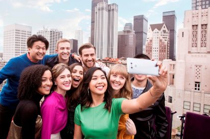 A group of people take a group selfie with the LG G6 in Ice Platinum in front of the New York skyline